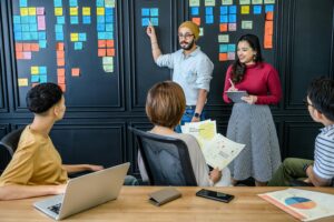 A diverse team collaborates on a project in an office, using sticky notes for brainstorming.