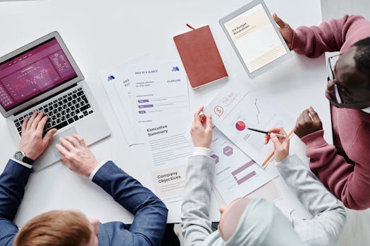 pexels-photo-7109241-7109241 Top view of a diverse team collaborating on digital devices and papers in an office setting.